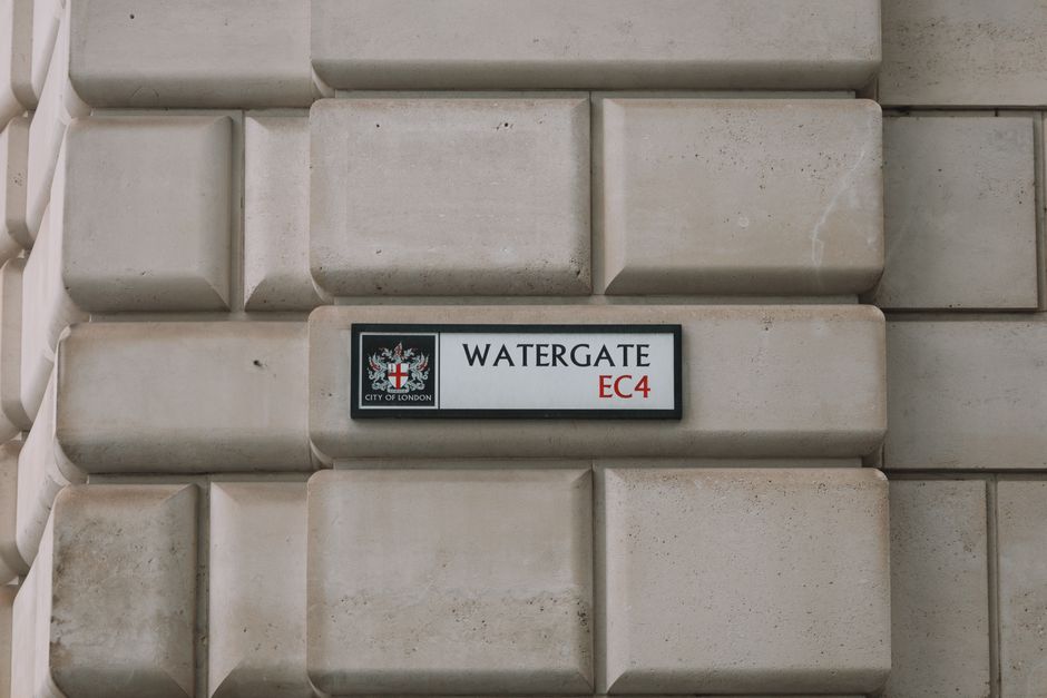 A close-up of a building wall made of large, smooth, beige stone blocks with rounded edges, displaying a rectangular street sign for Watergate in the EC4 postal district of the City of London. The sig